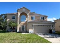 Two story home featuring an arched entryway, attached two-car garage, and front lawn at 402 Big Sioux Ct, Kissimmee, FL 34759