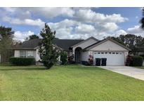 Charming single-story home with a well-manicured lawn, blossoming bushes, and attached two-car garage at 8647 Black Mesa Dr, Orlando, FL 32829