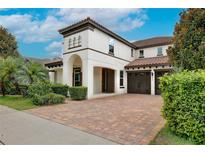 Stunning two-story home with a red tile roof, lush landscaping, and a brick paver driveway and two-car garage at 8752 Lookout Pointe Dr, Windermere, FL 34786