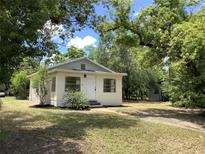 Charming single-story home with a white exterior, surrounded by mature trees and lush greenery at 200 W Doane Ave, Eustis, FL 32726