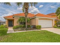 Charming single-story home with a terra cotta roof, palm trees, and a well-manicured lawn at 214 Paloma Dr, Davenport, FL 33837