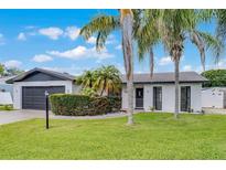 Charming single-story home featuring a well-manicured lawn and mature landscaping with palm trees at 2932 Carriage Dr, South Daytona, FL 32119