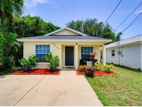 Charming yellow home with inviting front yard and vibrant landscaping under a clear blue sky at 5123 Pineland Ave, Port Orange, FL 32127