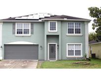 Two-story home featuring a gray front door, a two-car garage, solar panels and manicured green lawn at 115 Willowbay Ridge St, Sanford, FL 32771