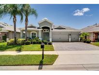 Charming single-story home featuring a three-car garage, tropical landscaping, and a paver driveway at 15521 Sandfield Loop, Winter Garden, FL 34787