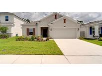 Beautiful one-story home featuring a manicured lawn, flower beds, and a two-car garage at 2043 Rock Maple Bnd, Kissimmee, FL 34746