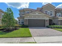 Lovely two-story home features a two-car garage, brick-paved driveway, manicured lawn, and beautiful landscaping at 2122 Bent Grass Ave, Ocoee, FL 34761