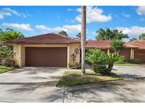 Charming home featuring a brown garage door, beautiful landscaping, and a red tile roof at 5059 Jamaica Cir # 15, Orlando, FL 32808