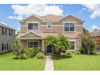 Charming two-story tan home with a well-manicured lawn and lush landscaping at 1030 Bending Oak Trl, Winter Garden, FL 34787