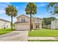 Charming two-story home featuring a well-manicured lawn and beautiful palm trees at 14425 Huntingfield Dr, Orlando, FL 32824
