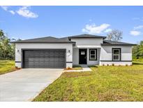 Charming single-story home with a gray garage door, black trim and a well-manicured lawn and inviting curb appeal at 15684 Sw 37Th Cir, Ocala, FL 34473