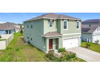 Two-story home featuring an attached two car garage, neutral colored paint, and well-maintained landscaping at 1808 Post Oak Dr, Davenport, FL 33837