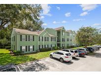 Green apartment building with black shutters, a well-manicured lawn, and ample parking on a sunny day at 2035 Dixie Belle Dr # 2035C, Orlando, FL 32812
