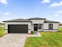 A modern home features a two car garage, gray brick paver driveway, and manicured lawn at 4662 Sw 136Th St, Ocala, FL 34473
