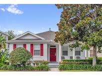 Charming single-story home featuring a red front door, decorative shutters, and a well-maintained landscaped yard at 7416 Soiree Way, Reunion, FL 34747