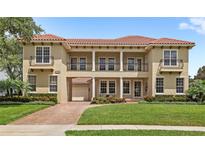 Stunning two-story home boasts a tile roof, manicured lawn, covered portico, and charming second-story balconies at 8424 Lake Burden Cir, Windermere, FL 34786