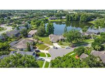 Aerial view of the home with lush landscaping, and a serene lake backdrop at 1125 Almond Tree Cir, Orlando, FL 32835