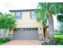 Two-story home with a grey garage door, lovely landscaping, and nice brick paver driveway at 1929 Nice Ct, Kissimmee, FL 34747