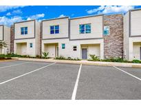 Modern townhomes featuring stone accents, neutral colors, and ample parking space, complemented by vibrant landscaping at 359 Famagusta Dr, Davenport, FL 33896