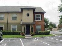 Two-story condo with manicured bushes, neutral paint, and dedicated parking spaces in front of the unit at 5953 Westgate Dr # 1821, Orlando, FL 32835