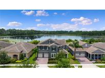 Stunning two-story home featuring lake views, a red brick driveway, and a well-manicured lawn at 10180 Merrymeeting Bay Dr, Winter Garden, FL 34787
