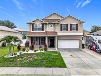 Two-story home featuring a landscaped front yard, brick accents, and attached two-car garage at 238 Hunt St, Clermont, FL 34711