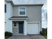 Two-story townhome with a one car garage, blue front door, and neutral color scheme at 1314 Isleta Loop, Kissimmee, FL 34741