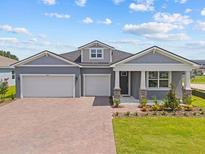 Charming single-story home with a well-manicured lawn, brick driveway, and a two-car garage at 2627 Ginseng Ivy St, Apopka, FL 32703