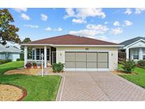 Charming single-story home with a well-manicured lawn, brick driveway, and a lovely screened-in garage at 4738 St Andrews Arc, Leesburg, FL 34748
