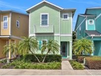 Charming two-story home featuring light green color, decorative shingles, a small balcony, and lush tropical landscaping at 8061 Lost Shaker Ln, Kissimmee, FL 34747