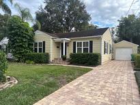 Charming home featuring a quaint front yard and a detached garage with a brick paver driveway at 230 E Esther St, Orlando, FL 32806