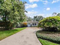 Charming single-story home with a well-manicured lawn, mature trees, and a welcoming blue front door at 2823 Wright Ave, Winter Park, FL 32789