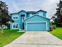 Two-story blue home featuring an attached garage, well-maintained lawn, and classic architectural details at 29 Catalina Ct, Kissimmee, FL 34758