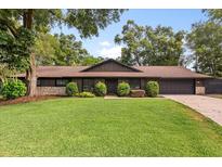 Beautiful single-story home with a well-manicured lawn, stone accents, and mature trees at 4 Hudson Cv, Longwood, FL 32750
