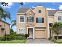 Inviting two-story home with stone accents, manicured lawn, and a paver driveway leading to an attached garage at 1011 Wood Cv, Kissimmee, FL 34743