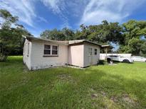 A side view of a weathered single-story home with peeling paint surrounded by lush greenery and blue skies at 2630 Ralph Rd, Lakeland, FL 33801