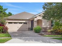 Charming single-story home with a two-car garage, arched entryway, and well-maintained landscaping at 7540 Bishop Square Dr, Winter Garden, FL 34787