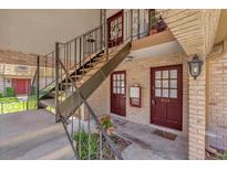 A welcoming apartment exterior featuring red doors, brick accents, and stairwell to the second level at 200 St Andrews Blvd # 802, Winter Park, FL 32792