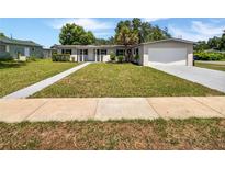 Charming single-story home with manicured lawn, a walkway to the front door and attached garage at 2607 Castle Oak Ave, Orlando, FL 32808