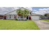 Charming single-Gathering home featuring a lush green lawn, palm trees, and a two-car garage at 643 Oregon Woods Ct, Orlando, FL 32824
