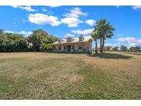 Charming home with a metal roof, dormers, and a wide front porch, surrounded by a green lawn and mature trees at 2198 W Highway 329, Citra, FL 32113