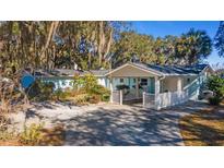 Light blue house with white accents, carport, and mature trees at 22345 Ne 108Th Avenue Rd, Fort Mc Coy, FL 32134