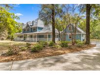 Two-story house with a wrap-around porch and mature landscaping at 7629 Sw 188 Ave, Dunnellon, FL 34432