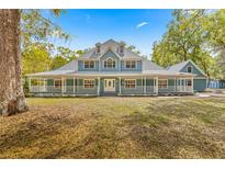 Charming blue home featuring a wrap-around porch, well-manicured lawn, and a symmetrical design at 7629 Sw 188 Ave, Dunnellon, FL 34432