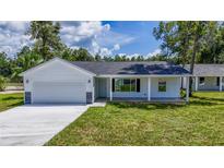 Newly built home with a covered porch and a gray stone accent at 13026 Ne 6 Pl, Silver Springs, FL 34488