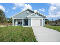 Charming single-story home with a well-manicured lawn, blue paint and a white garage door at 14409 Sw 30Th Pl, Ocala, FL 34481