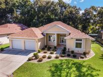 Well maintained house with two-car garage, landscaped front yard, and beige stucco exterior at 11017 Sw 71St Cir, Ocala, FL 34476