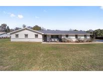 Charming single-story home with white exterior, well-maintained lawn, and inviting front porch with chairs at 4011 Se 47Th Pl, Ocala, FL 34480