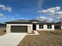 Charming single-story home with stone accents, gray roof, and two-car garage at 10131 Sw 41St Ave, Ocala, FL 34476
