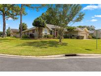 Charming single-story home featuring a lush green lawn, mature trees, and a well-maintained landscape at 2215 Se 24Th Ave, Ocala, FL 34471